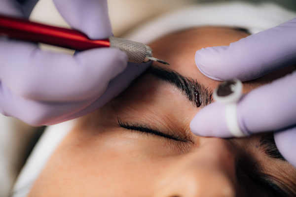 Young woman getting a microblading treatment in her eyebrows