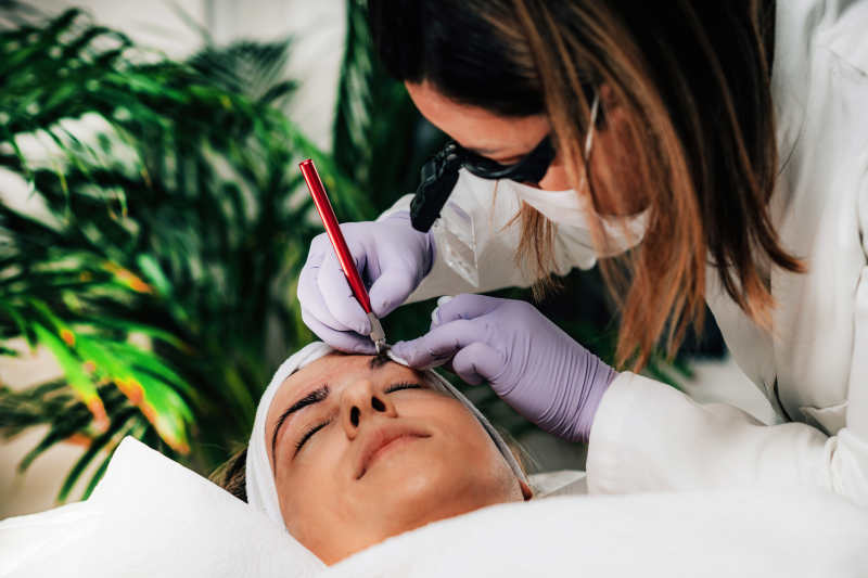 aesthetician performing microblading technique in a female customer